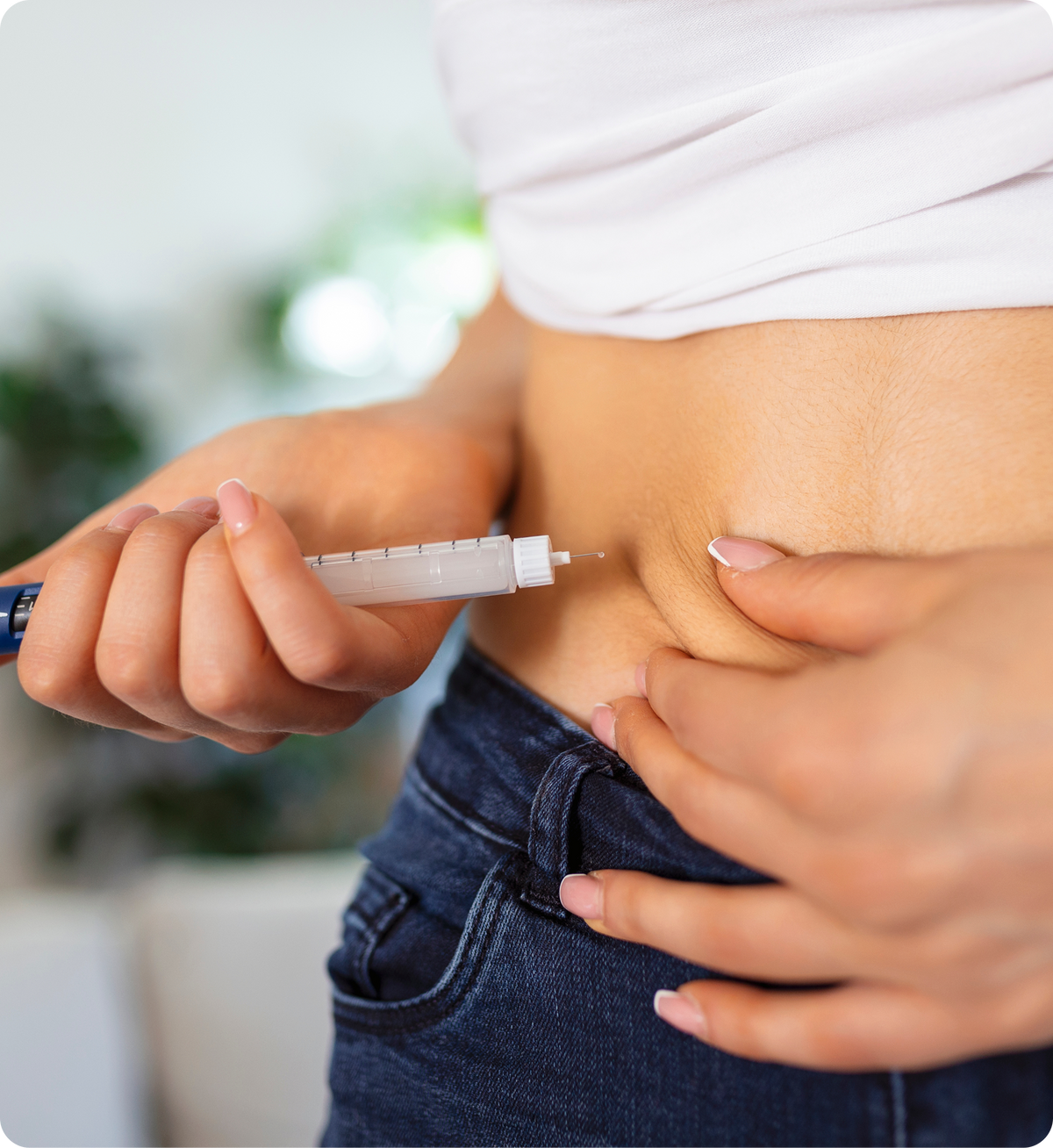 Hand holding syringe for subcutaneous injection into bare lower abdomen, pinching skin