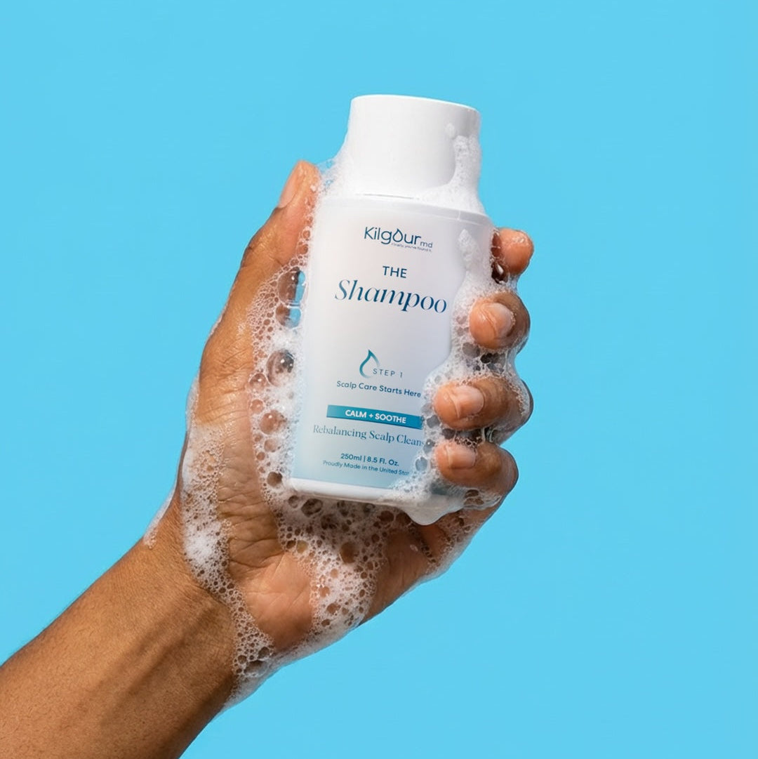 Hand holding a bottle of Klorane shampoo with a blue background